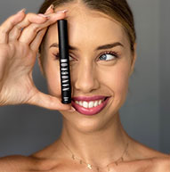 Uśmiechnięta modelka zasłaniająca oko butelką odżywki Nanobrow