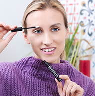 Modelka blondynka w fioletowym swetrze używająca serum do brwi