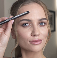 Blond modelka trzymająca pióro Microblading Pen przy czole