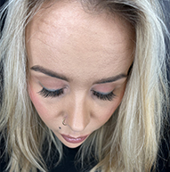 Kobieta o blond włosach i kolczyku podkreślającym długie rzęsy i odważny styl.