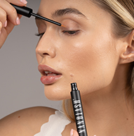Modelka patrzy w dół i nakłada odżywkę do rzęs Nanolash